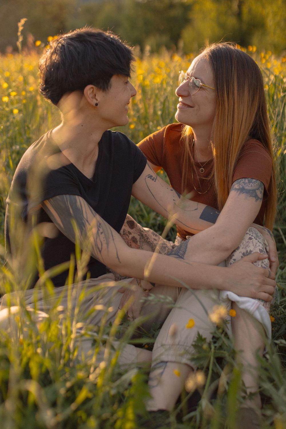 Nadège et Louisa assises dans les herbes hautes, elles se regardent en souriant